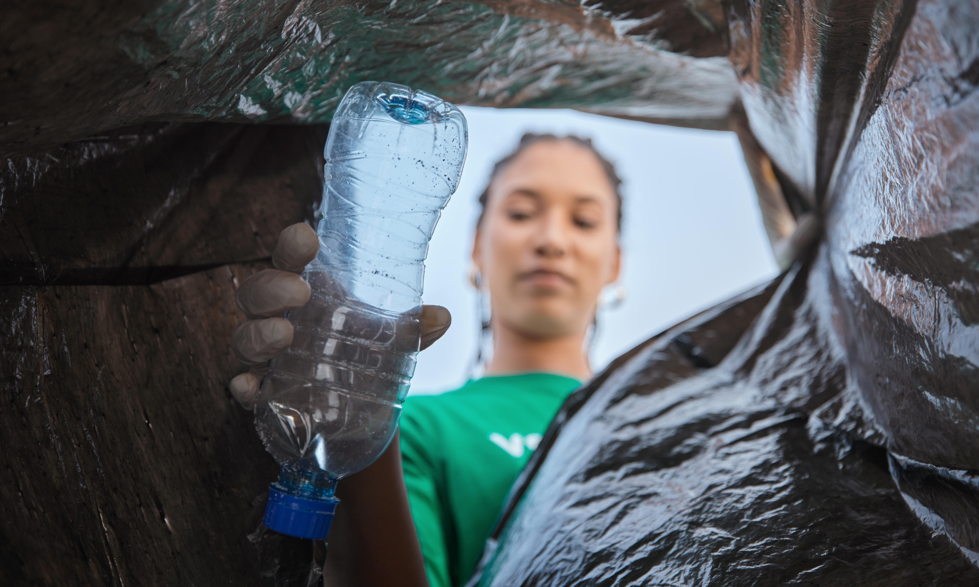 Woman placing empty plastic bottle in bin