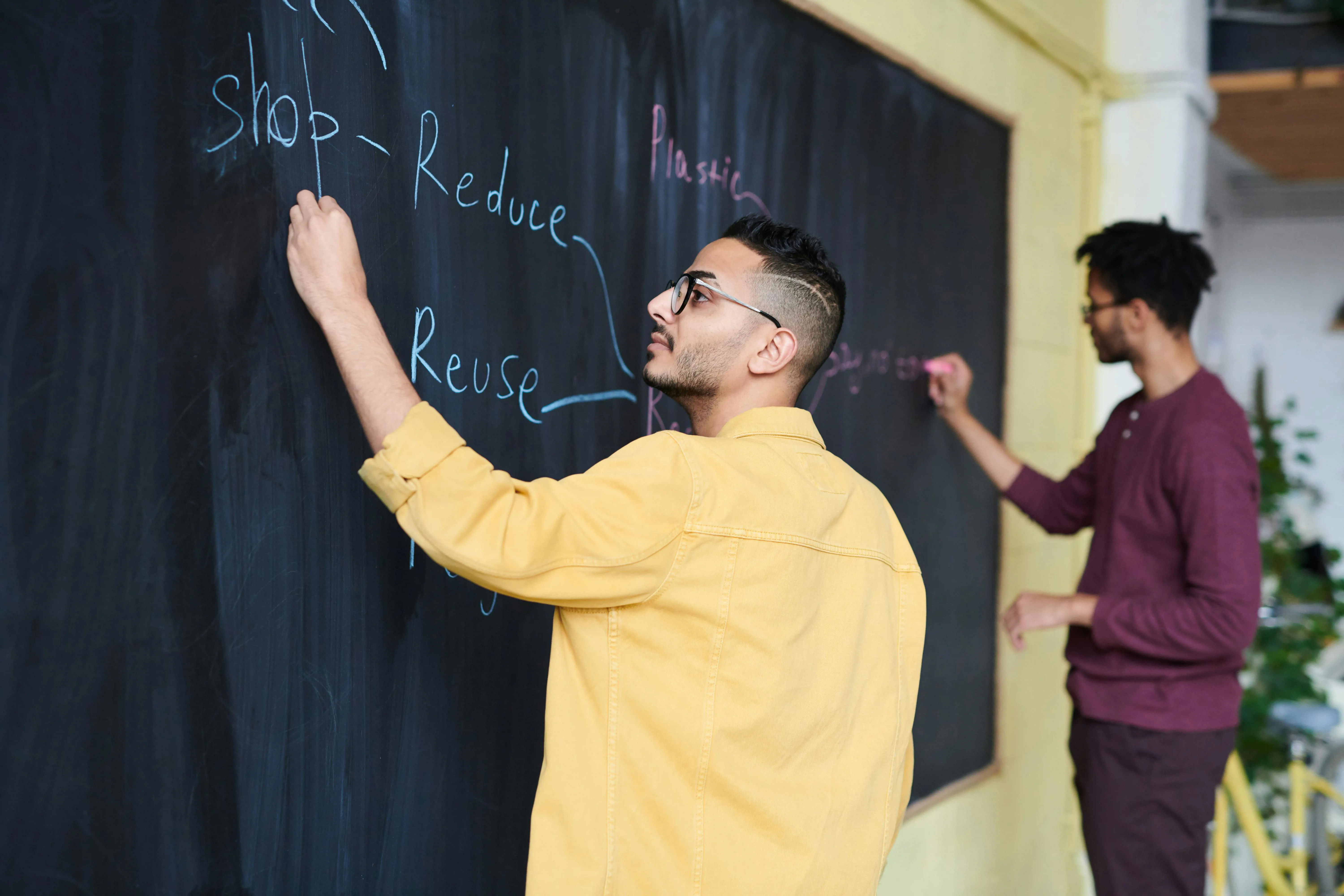 men writing on chalkboard