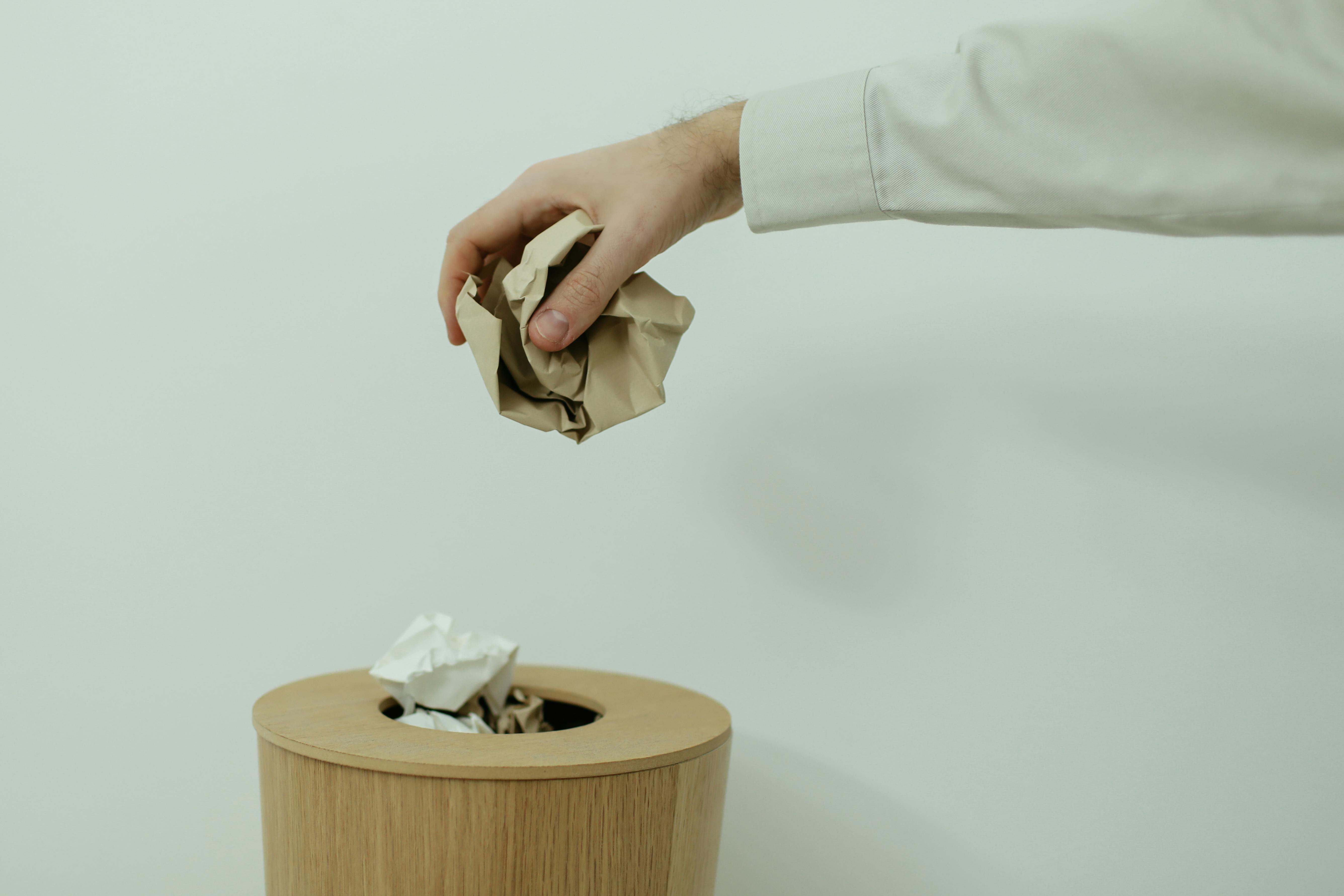 Close Up Photo Of Person Throwing Paper into a Bin