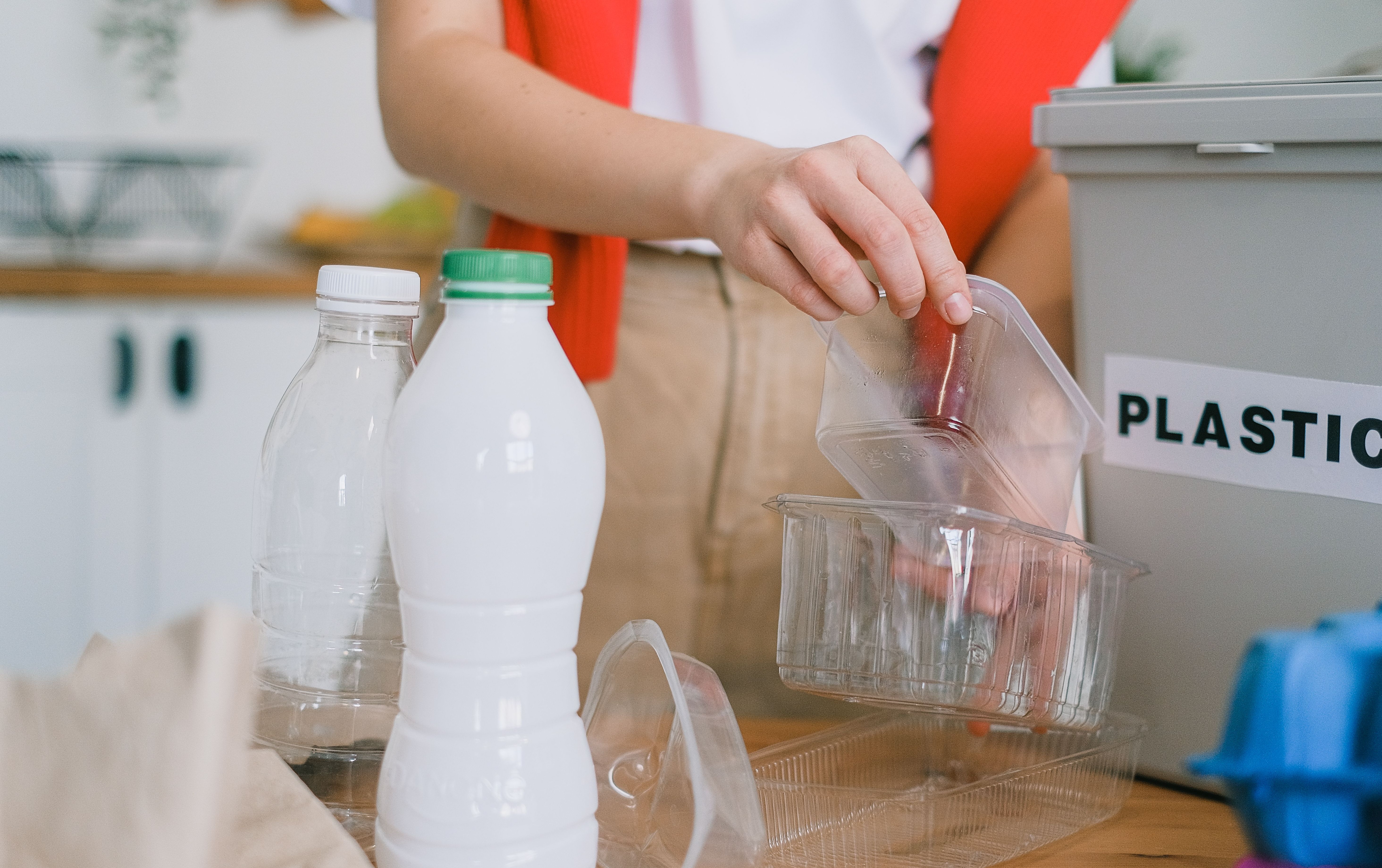 woman placing plastic into plastic recycling bin