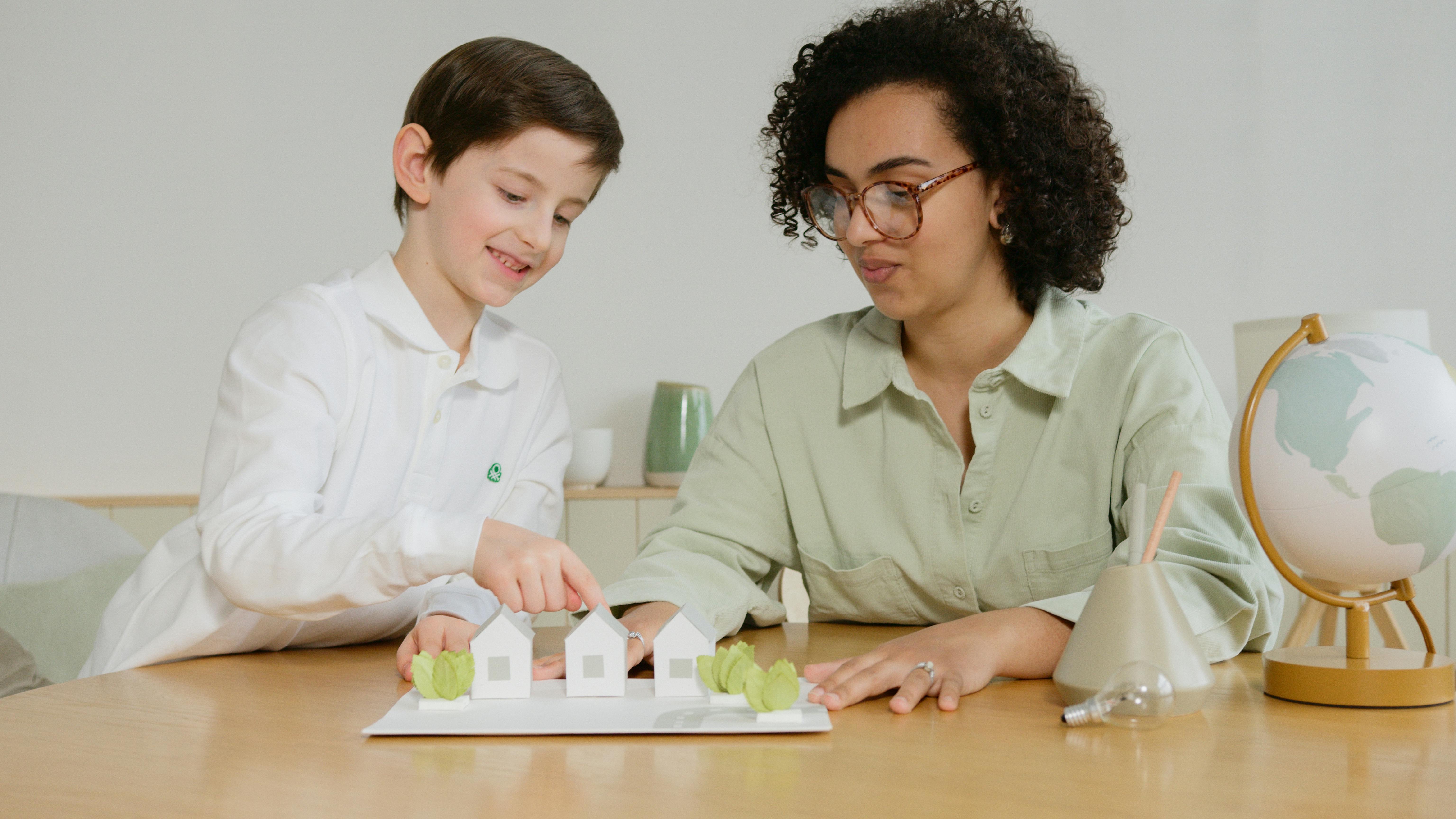 child and teacher with paper houses project