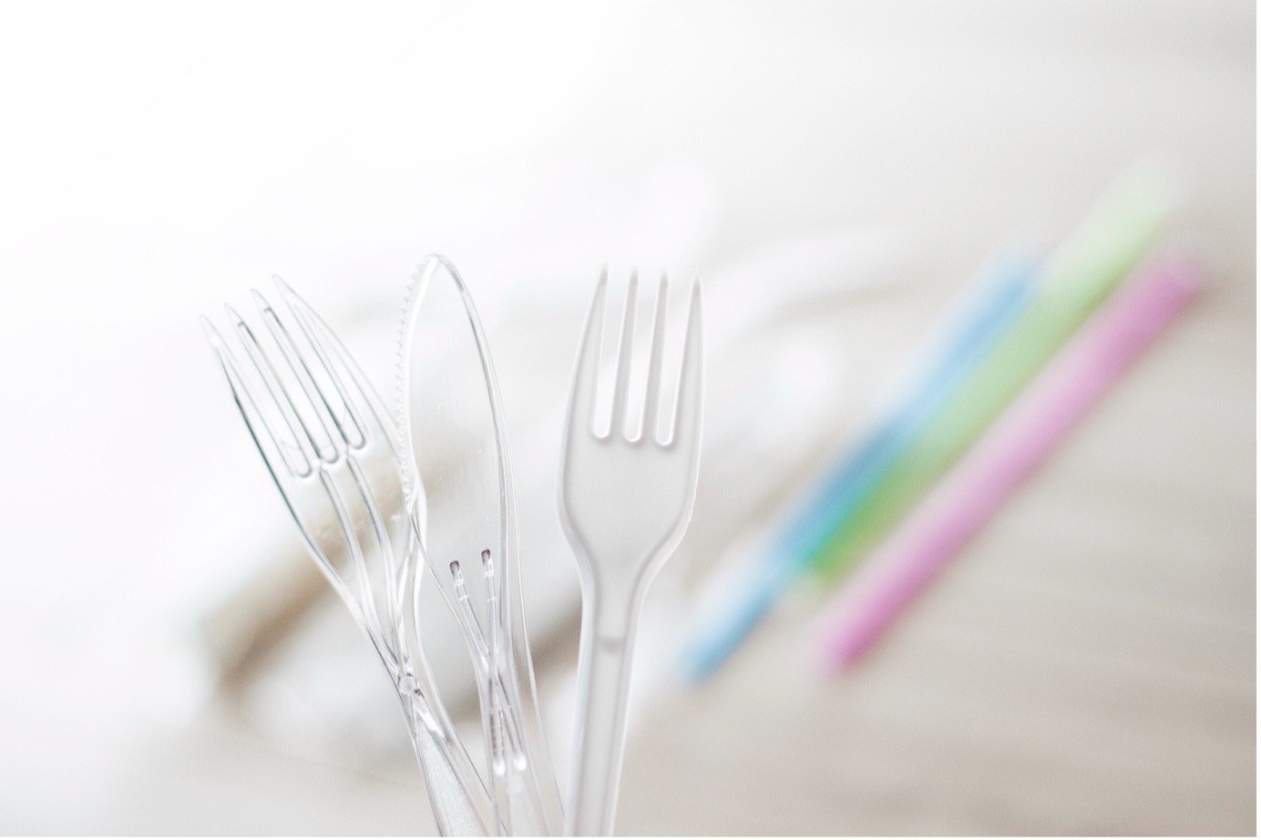 Plastic cutlery in front of plastic straws