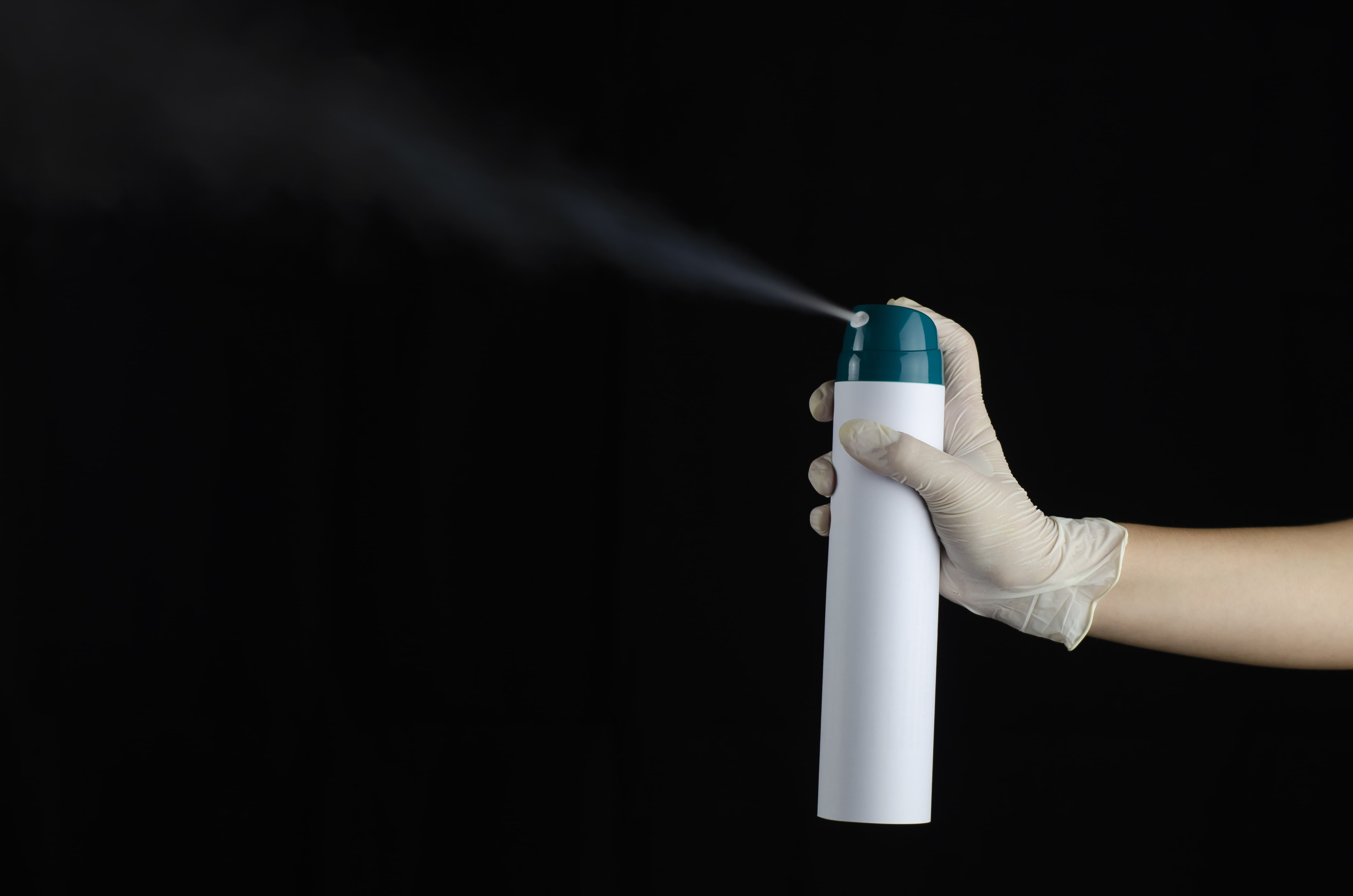 Person wearing gloves using disinfectant spray